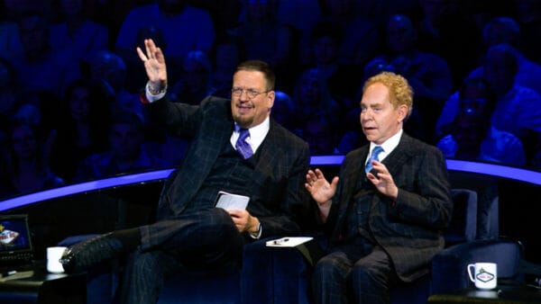 Penn & Teller sitting on stage in suits