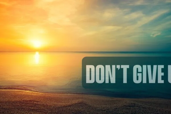 Finding Light in the Darkness Sunrise with ocean and sand and words that say don't give up