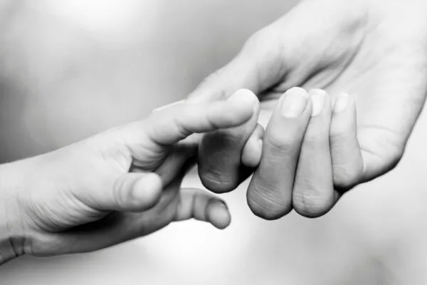 From Doomscrolling to Hopescouting: A Better Way Forward Black and white close up photo of two hands reaching for each other and holding on