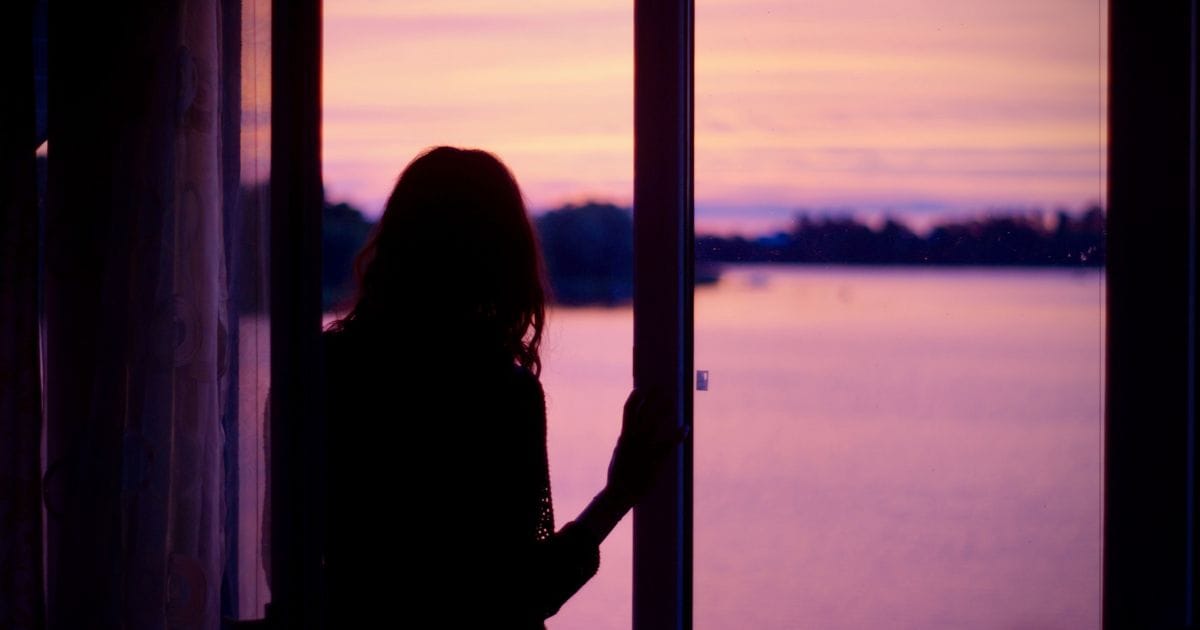 A silhouette of a woman gazing out a window at dusk or dawn, suggesting longing, contemplation, and the search for answers.