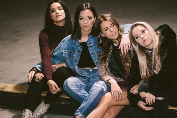 The Aces Drop “Twin Flame” and Light a Disco-Pop Fire for the Summer Group shot of the Aces band sitting on a curb, four women