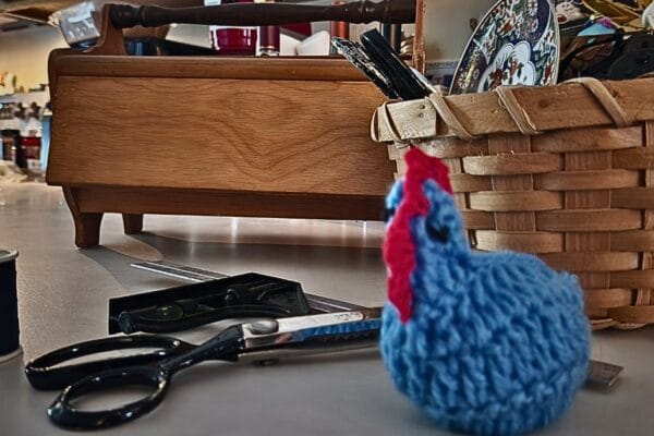 Navy blue thread, fabric scissors and a crochet blue hen with a sewing kit