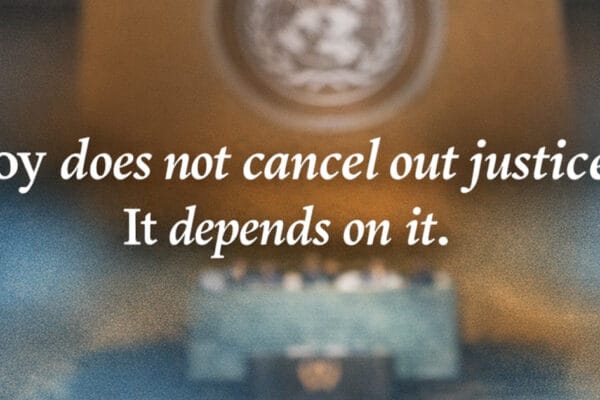 Blurred view of the United Nations General Assembly chamber with white text reading, “Joy does not cancel out justice. It depends on it.”