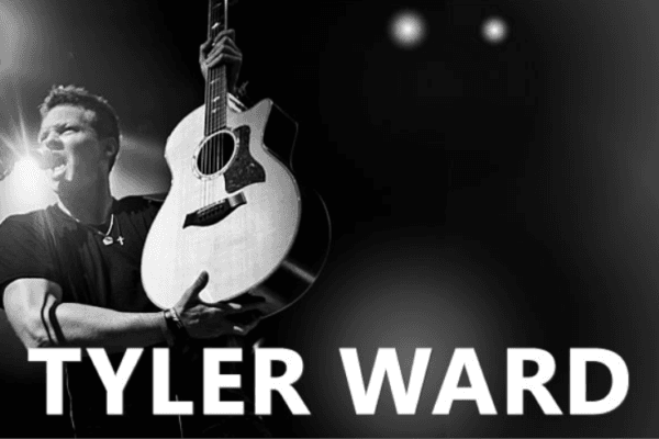 Black and white Tyler Ward on stage with an acoustic guitar